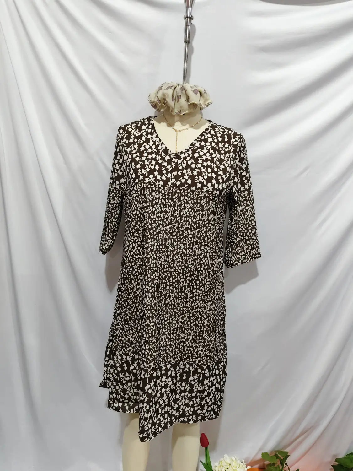 Une robe midi à imprimé floral noir et blanc, avec une encolure en V, des manches trois-quarts et un ourlet asymétrique.