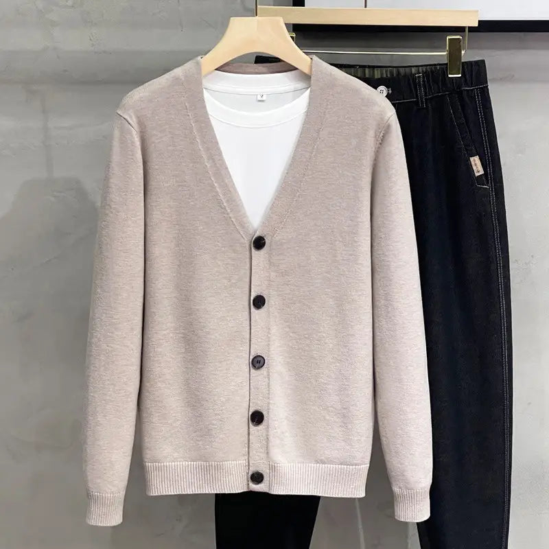 Beiger Herren-Strick-V-Neck-Cardigan-Sweater-Mantel mit dunklen Knöpfen und gerippten Bündchen aus Strickstoff gefertigt.