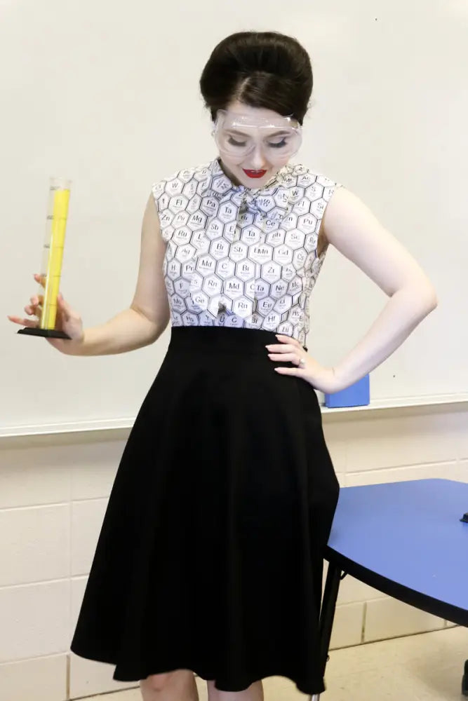Yellow graduated cylinder with black base next to a charlotte nova black high waisted pleated ponte skirt