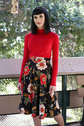 A woman wears a red long-sleeved turtleneck with a charlotte black floral 1950s vintage style circle skirt