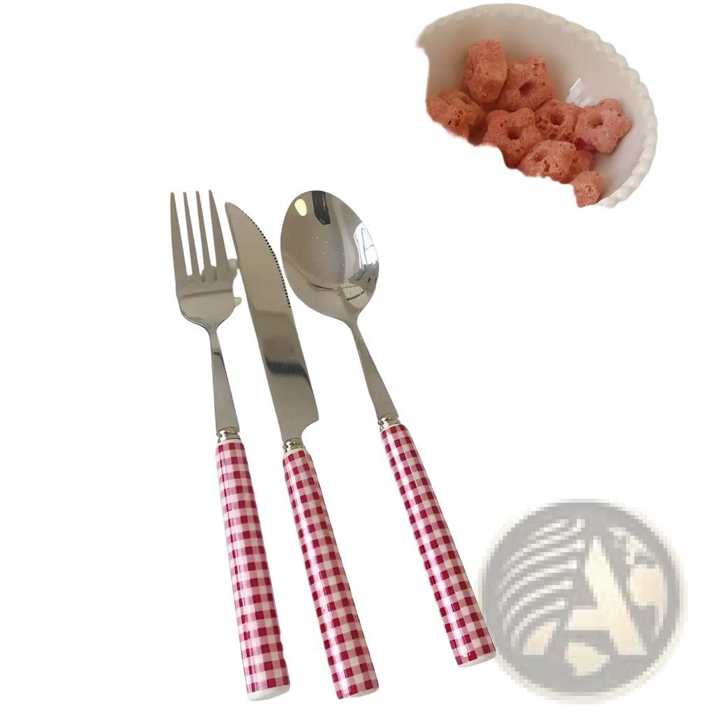 Set of three stainless steel cutlery pieces with red and white gingham handles on a scalloped white plate