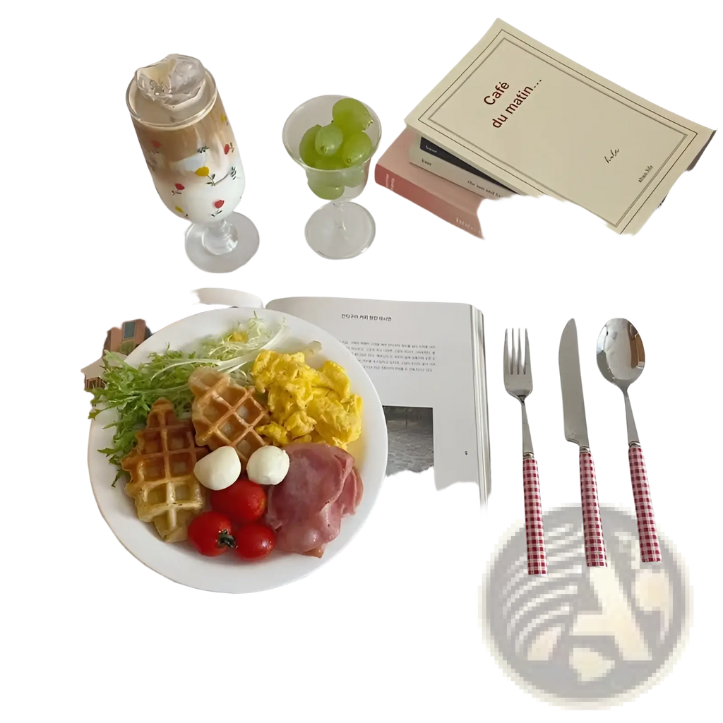 White plate with waffle scrambled eggs ham tomatoes and mozzarella balls alongside checkered stainless steel cutlery set