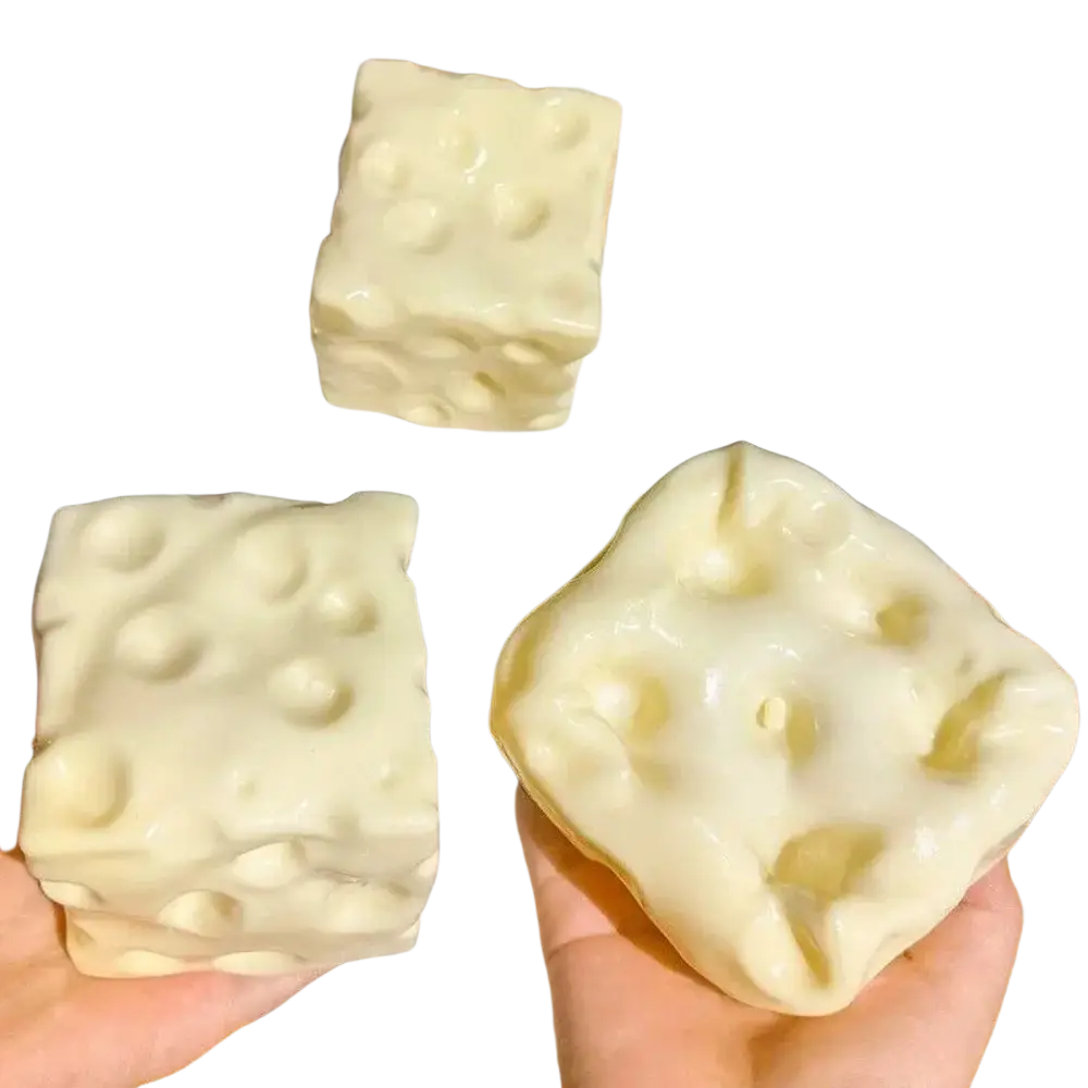 Cream-colored cheese block stress relief squeeze toy shaped like cheese with textured holes and bumps for stress relief