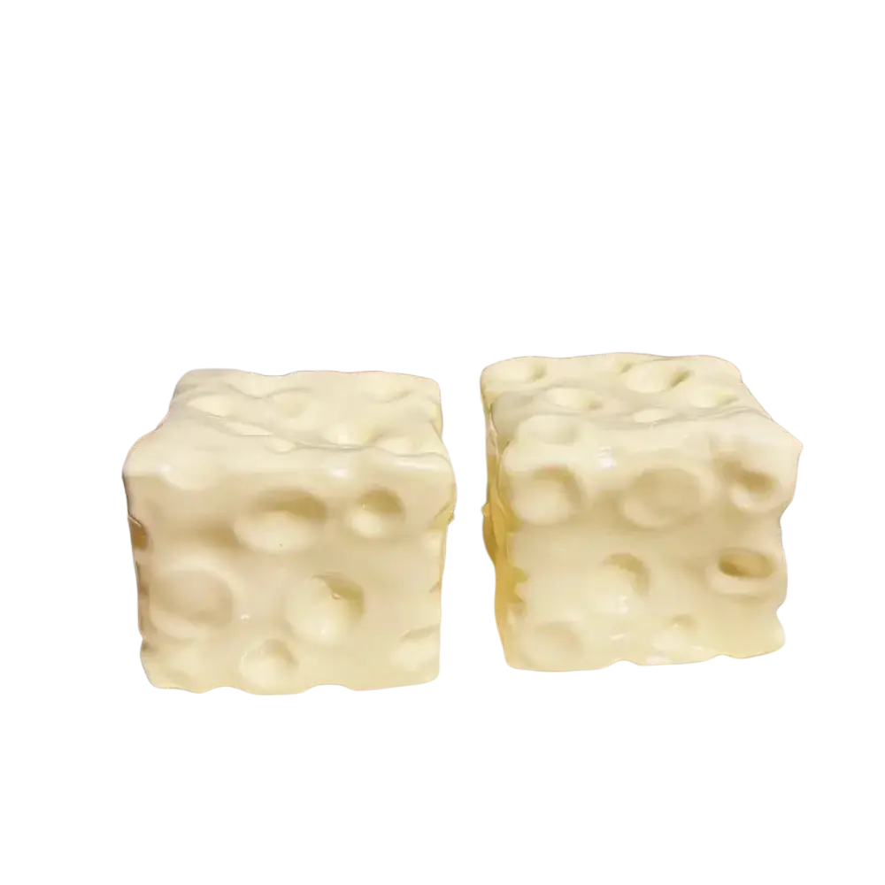 Two creamy white cheese block stress relief squeeze toys with textured surface resembling swiss cheese holes on a plate