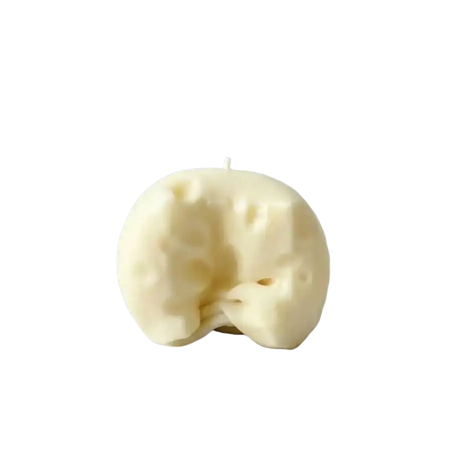 Cream-colored hand-crafted candle shaped like a whimsical apple with texture details featured alongside cheese cube stress ball