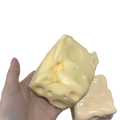 A pale yellow glossy cheese cube stress ball soap with textured holes designed as a cube stress ball sensory toy