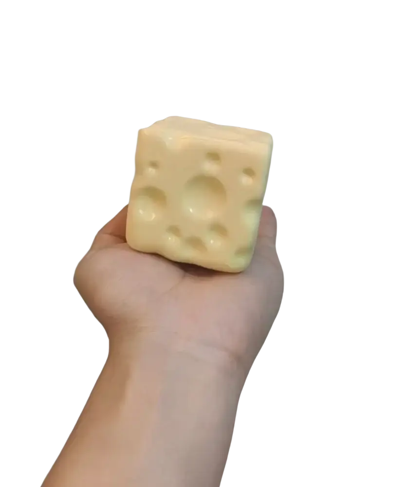 A pale yellow cheese cube stress ball with textured circular holes resembling swiss cheese for sensory use