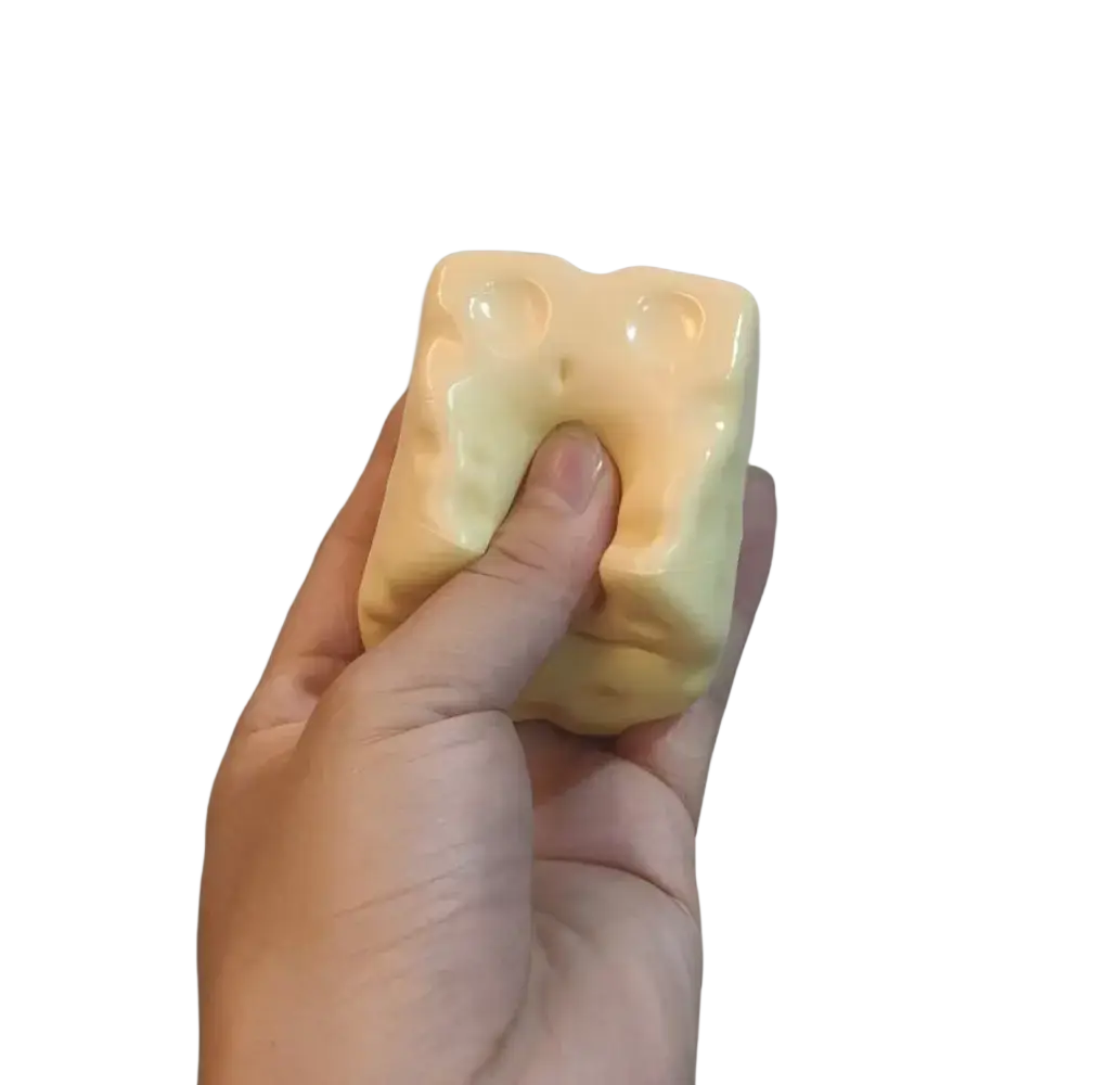 A pale yellow cheese cube stress ball with textured sponge material for sensory and stress relief use