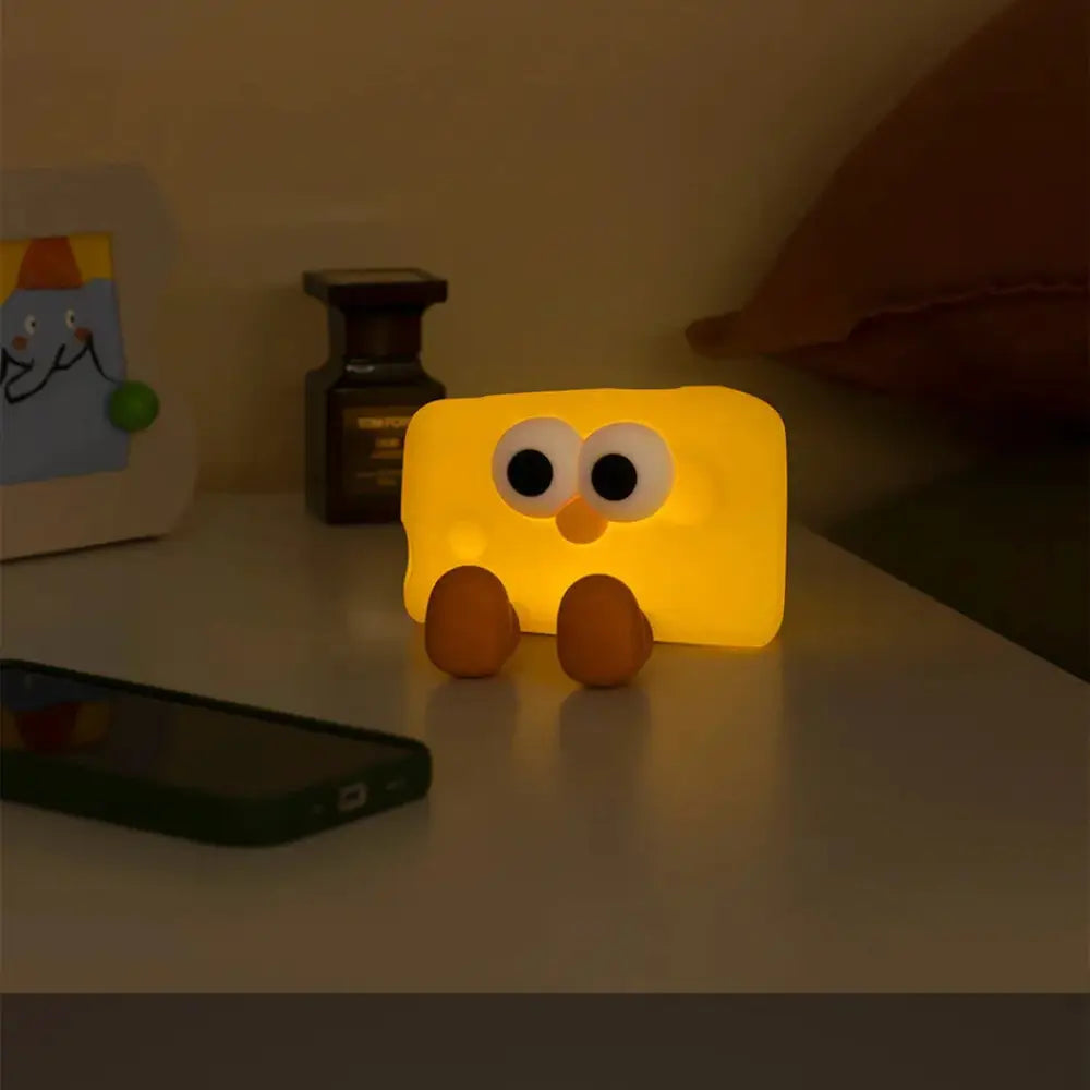 Yellow rectangular silicone led night light with large round eyes and brown feet for kids designed as cute cheese