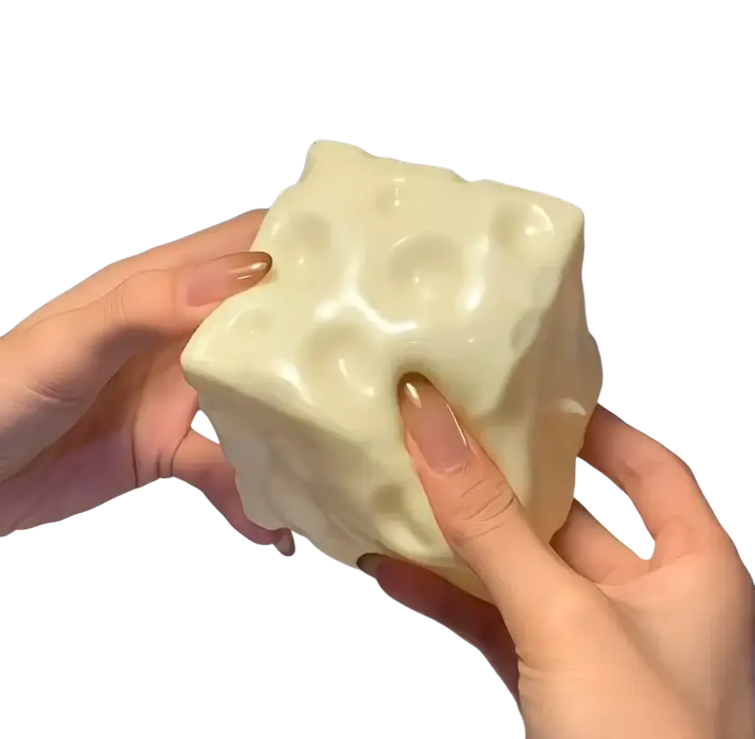 Cream-colored glossy plastic cheese squishy toy with textured cheese holes for slow rising sensory stress relief