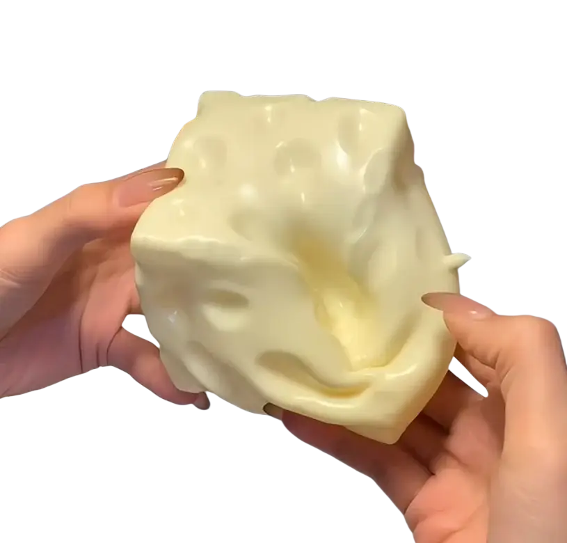 A creamy off-white silicone cheese squishy toy with textured holes for slow rising sensory stress relief