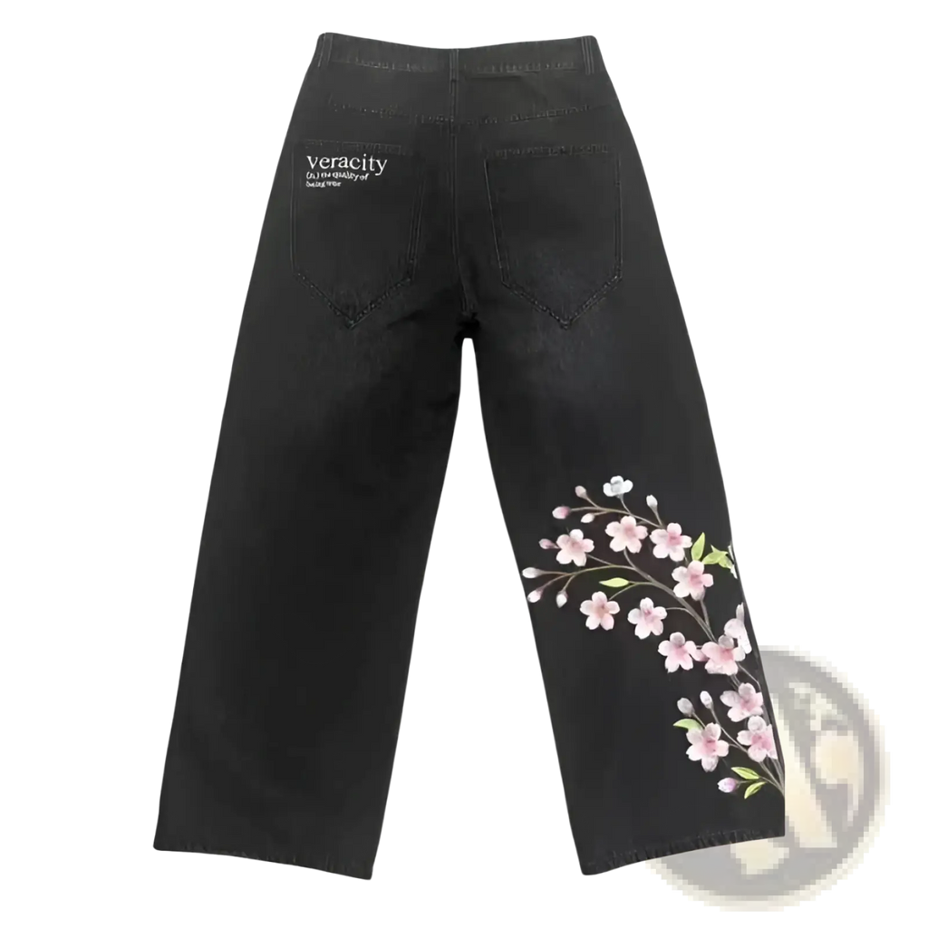 Black denim jeans with delicate pink cherry blossom embroidery on the lower leg from the front view