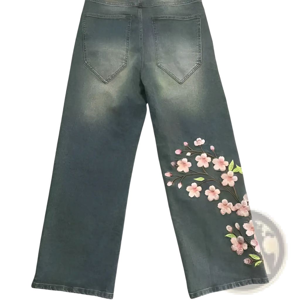 Dark-wash denim jeans with delicate pink cherry blossom embroidery along the outer seam display elegant retro style