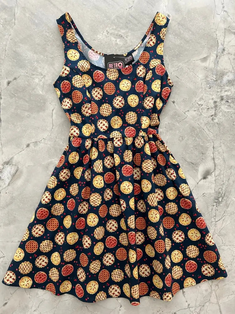 A navy blue sleeveless fit and flare mini dress with a playful golden and red cherry pie slice print