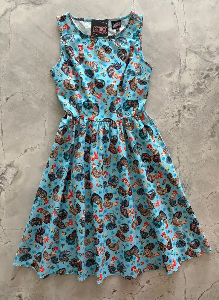 Vintage 1950s sleeveless light blue cotton a-line dress with colorful rooster print and gathered waistline with pockets