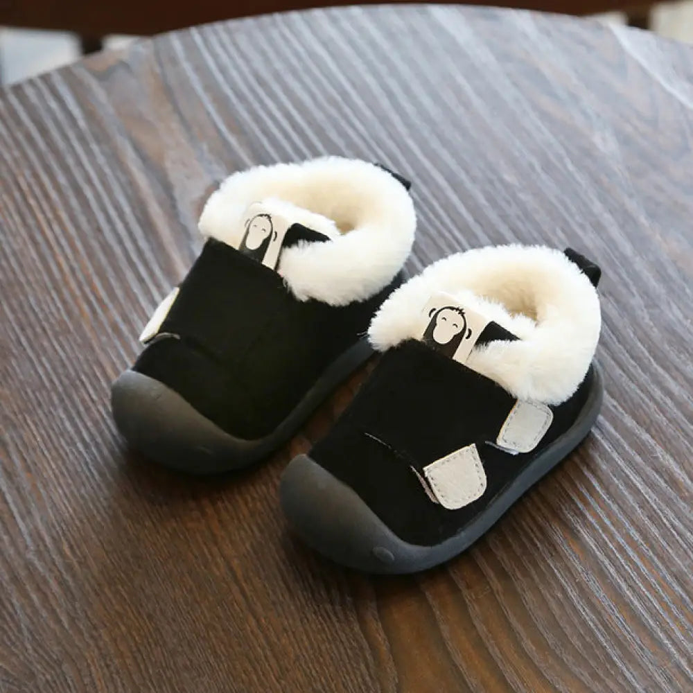 Black toddler snow boots with white plush faux fur lining and monkey face patches for cold weather use