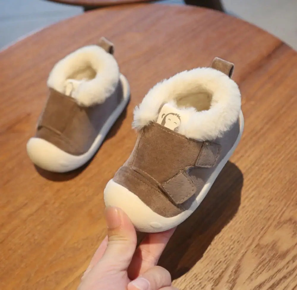 Brown suede toddler snow boots with plush white faux fur lining and monkey face patch on the inner side
