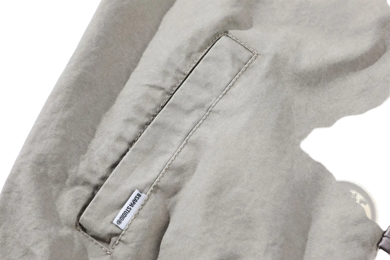 Beige canvas pocket with neat stitching and small white brand tag on a Chinese style men’s retro jacket