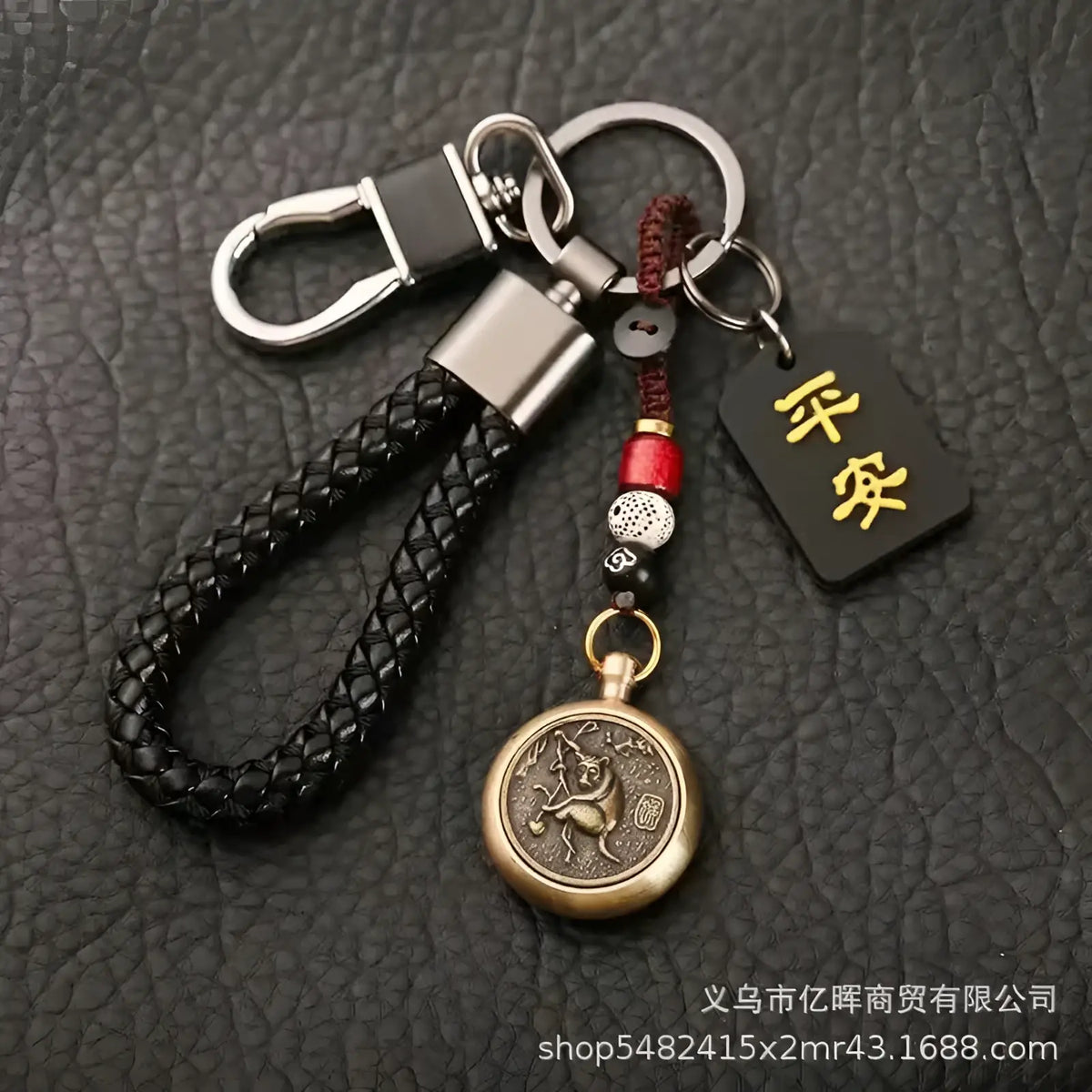 Black braided leather keychain with bronze circular engraved pendant red and black beads and gold chinese characters tag