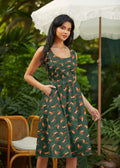 A woman wears a dark green chipmunks vintage fit and flare cotton dress with orange fox pattern and pockets