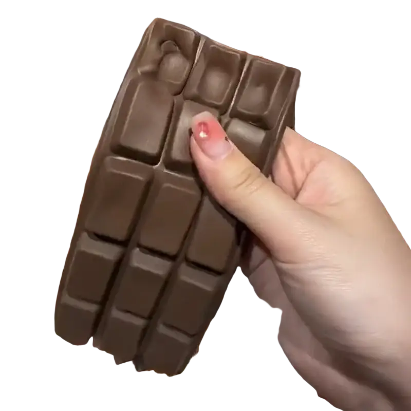 A hand holds a brown chocolate bar squeeze toy with segmented squares and rounded edges for sensory fidget use