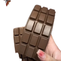 A hand holds a dark brown soft-textured chocolate bar squeeze toy with square segments for slow rising sensory fidget