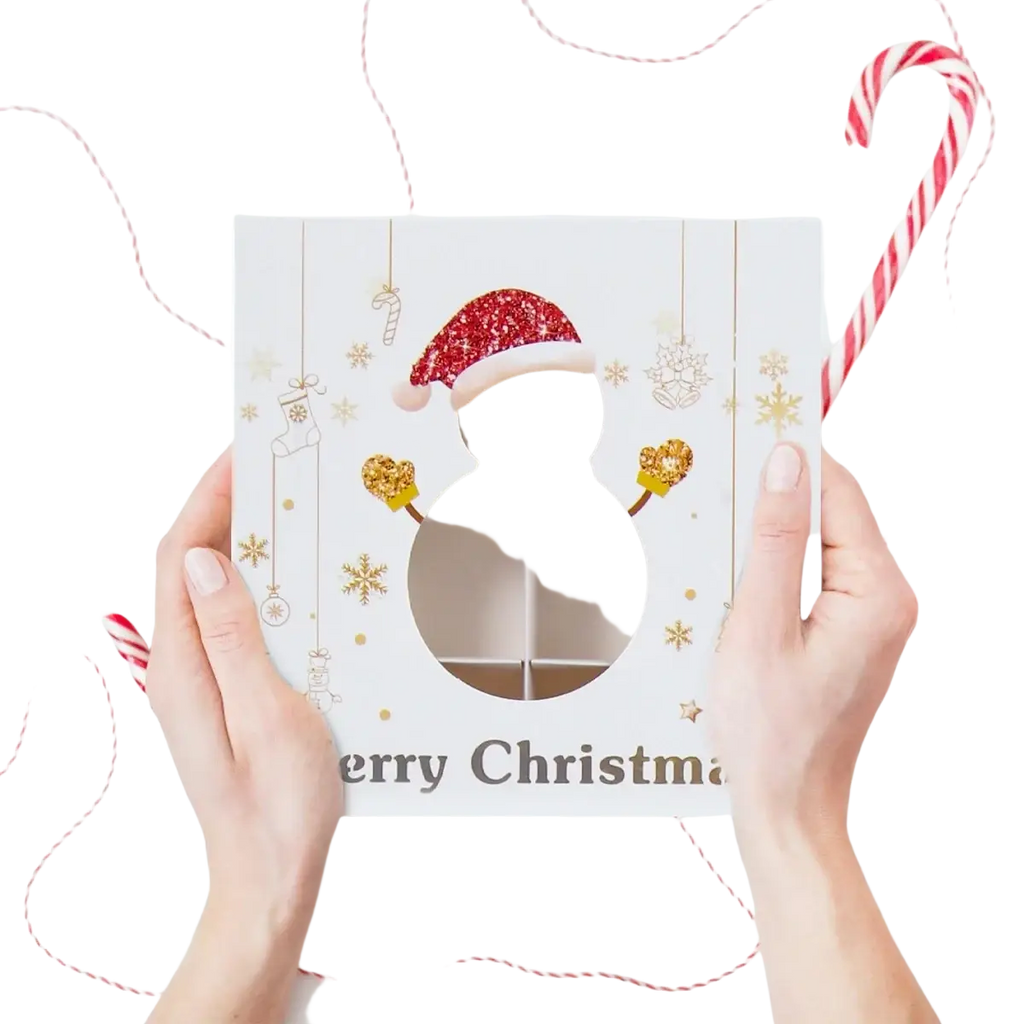 White christmas-themed paper gift box with clear six-compartment window, glittery red santa hat, and gold snowflake decorations for cookies