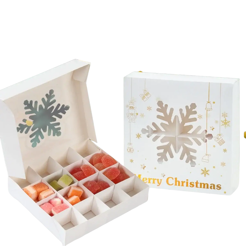 White christmas-themed paper gift box with snowflake design and gold accents containing colorful gummy candies