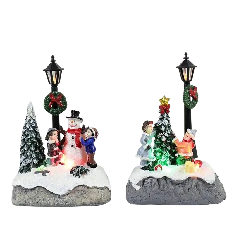 Two festive christmas house light led snowman figurine displays with detailed scenes of children and trees on rocky bases