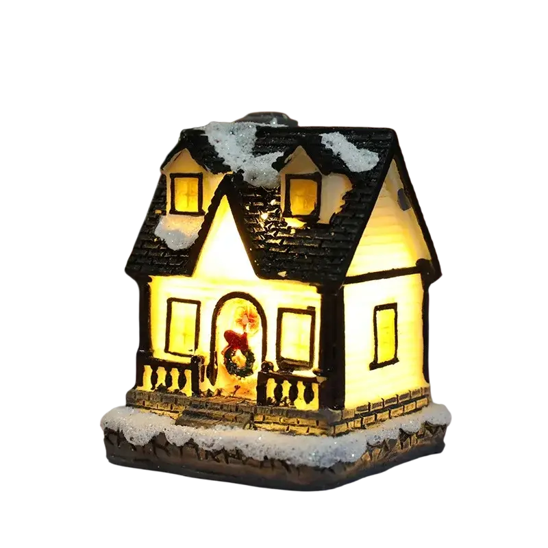 A warmly lit christmas house night light with black shingled roof, snow accents, glowing windows, and festive wreath decor