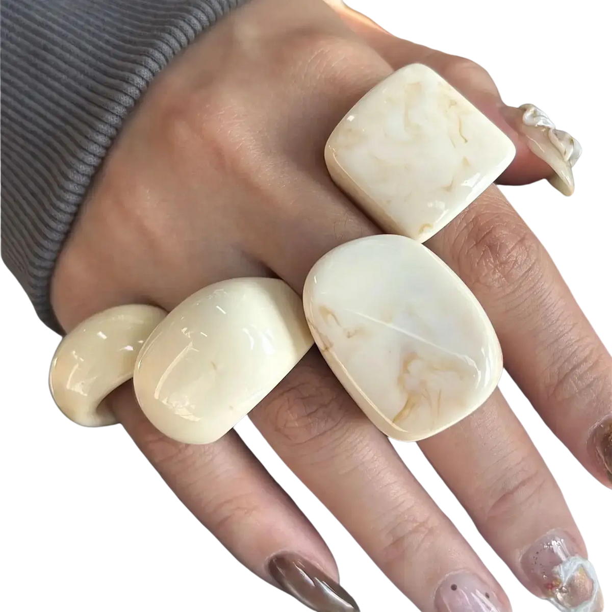 Cream-colored marbled resin chunky cocktail rings with smooth rounded edges worn on multiple fingers in a 4-piece set
