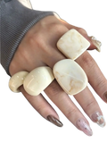 Cream-colored marbled chunky resin cocktail rings with smooth rounded edges worn on multiple fingers in 4-piece set
