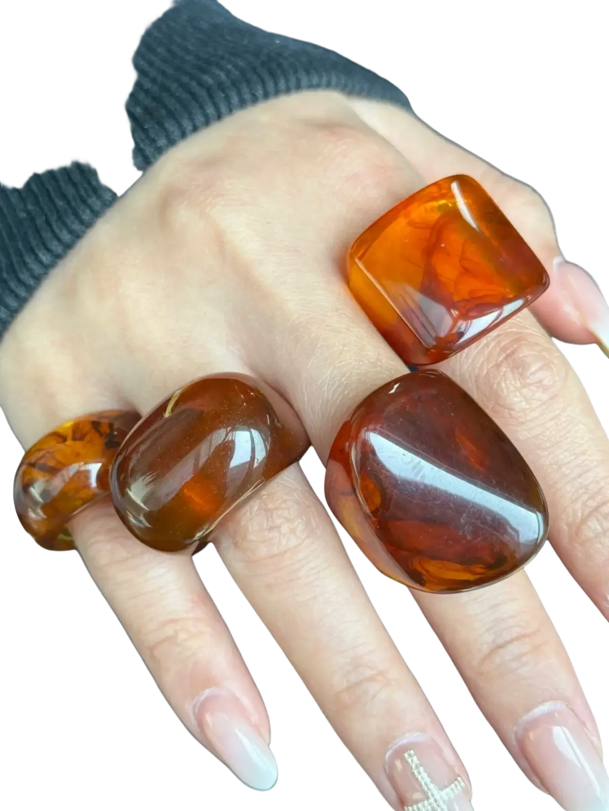 A hand wearing three bold amber chunky resin cocktail rings with smooth polished surfaces and natural marbled patterns