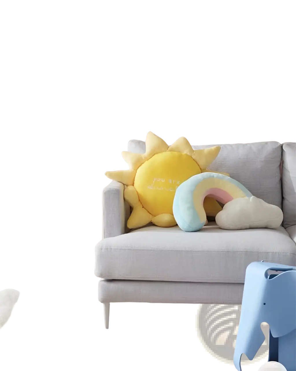 Soft yellow plush sun pillow with embroidered text and spiky rays resting on gray sofa for wall hanging decor