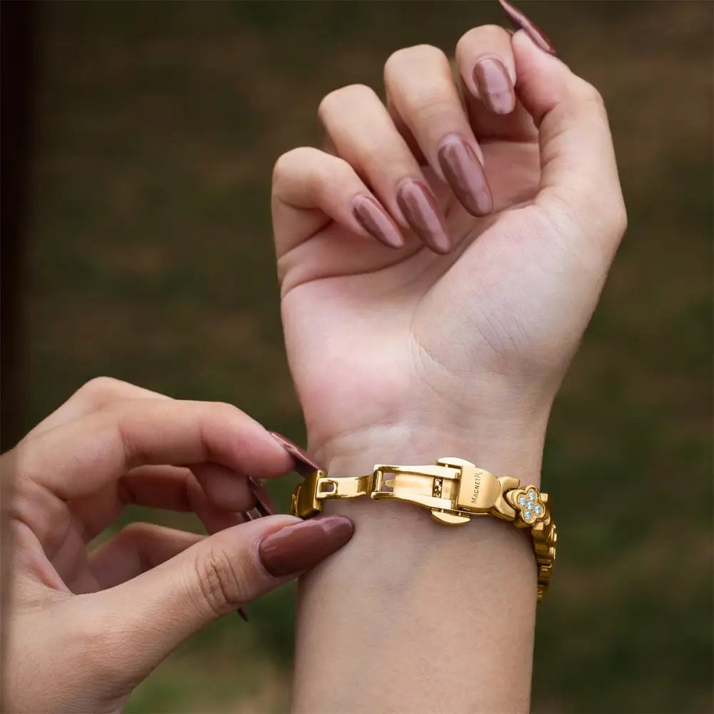 Gold crystal clover magnetic bracelet for women with gold-toned band and floral clasp adorned with clear stones