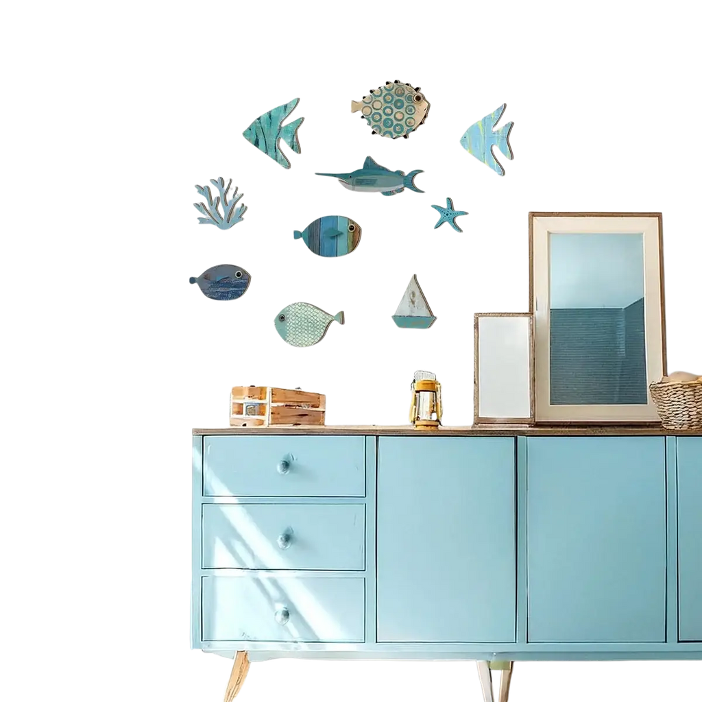 Blue painted wooden cabinet with three drawers and coastal style art fish shaped wall decor in blue and teal shades