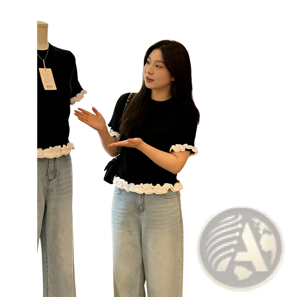Black short sleeve knit top with white ruffled trim at hem and cuffs featuring colorblock design