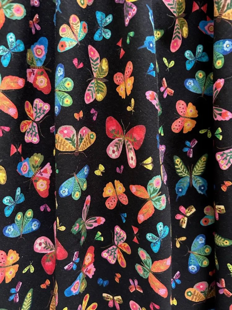 Black cotton v neck dress with vibrant multicolored butterfly print in pink blue orange and green by Greta