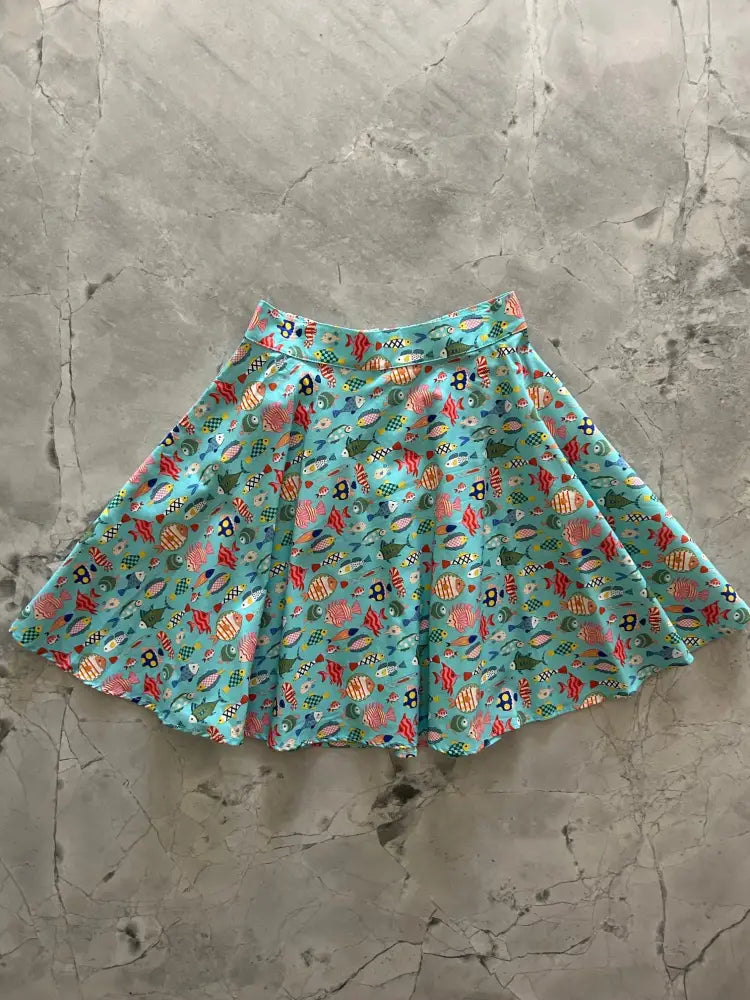 A teal colorful fish print vintage a line skater skirt with vibrant turquoise pleats and seaweed pattern