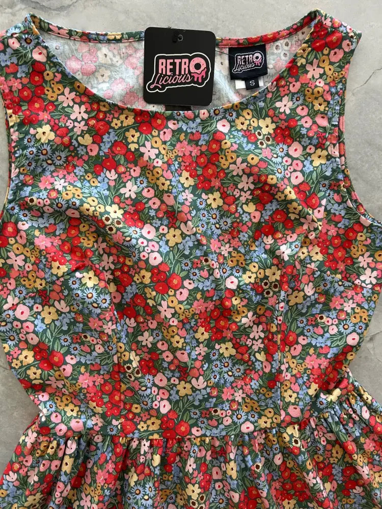 Vintage 1950s painted floral cotton a-line dress with pockets in vibrant red pink yellow and blue hues on dark background