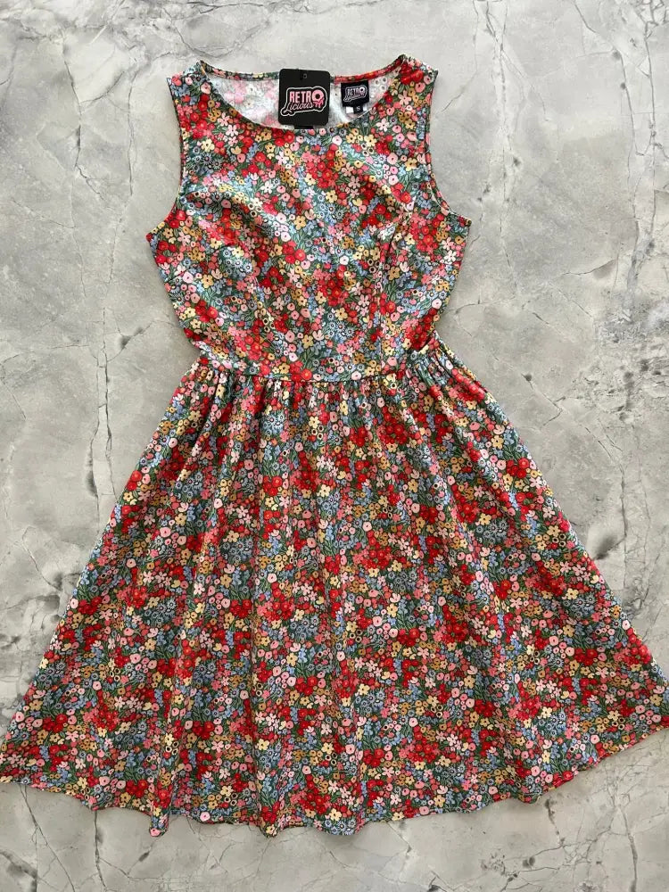 Vintage 1950s sleeveless cotton a-line dress with vibrant painted floral pattern in red pink blue yellow on dark green background