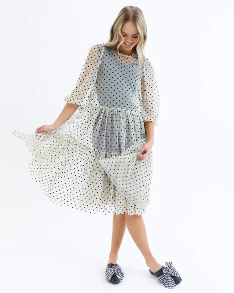 A woman wears a light blue and white polka-dot knee length contour shaping slip dress with sheer sleeves