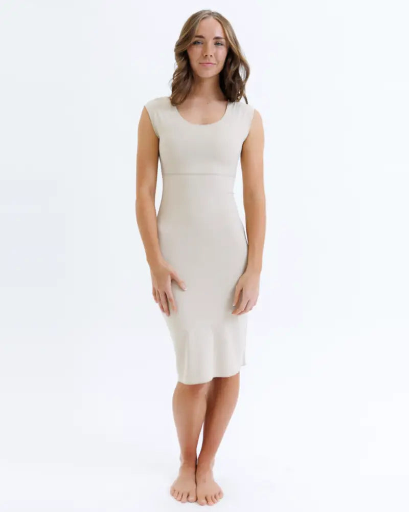 A sleek off-white seamless knee length contour shaping slip dress with a fitted silhouette and rounded neckline