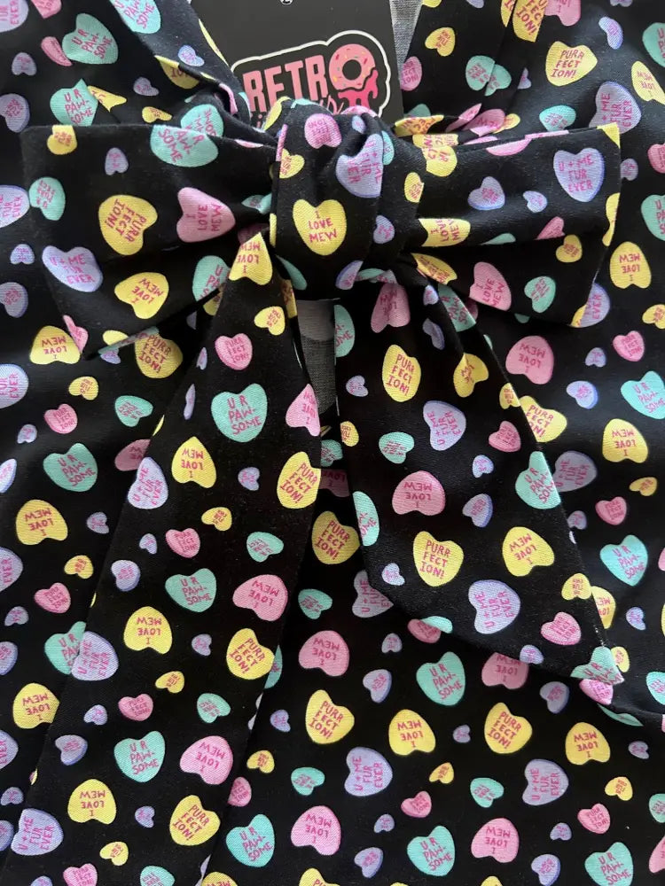 Vintage conversation hearts bow neck blouse featuring a black fabric bow with colorful heart candy print