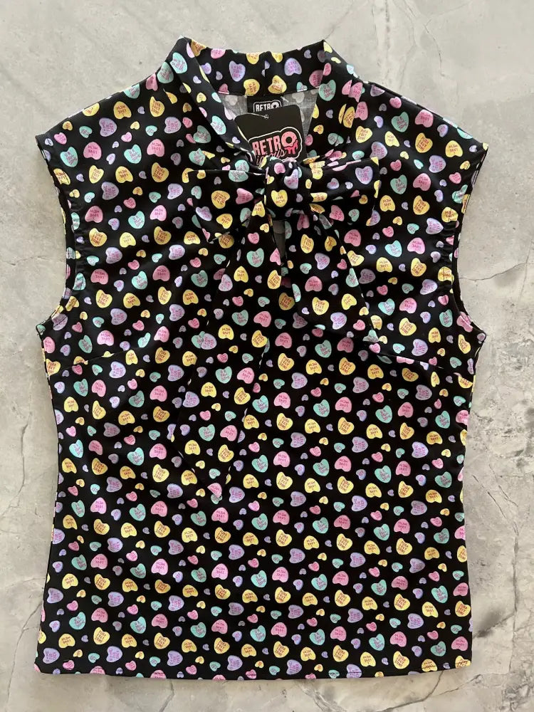 Black sleeveless vintage blouse with colorful candy heart pattern and bow at the neckline for stylish wear