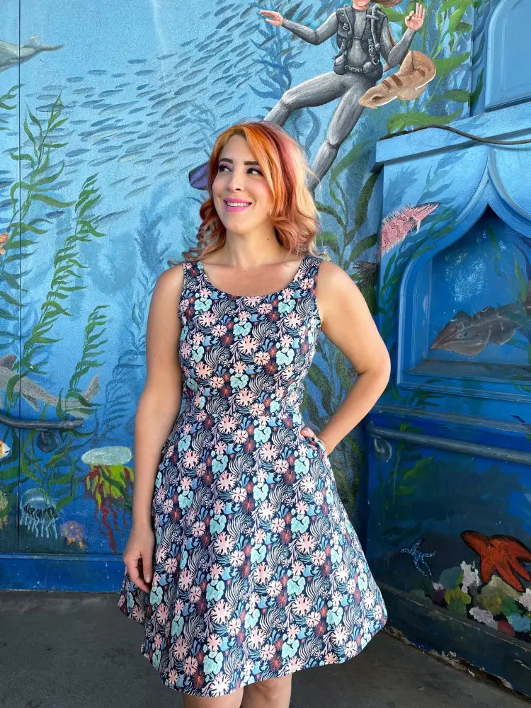 Coral floral sleeveless skater dress in navy blue fabric with vibrant pink light blue and white blossoms and pockets