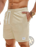 Beige corduroy drawstring shorts for men with white drawstrings and a small label on the lower right leg