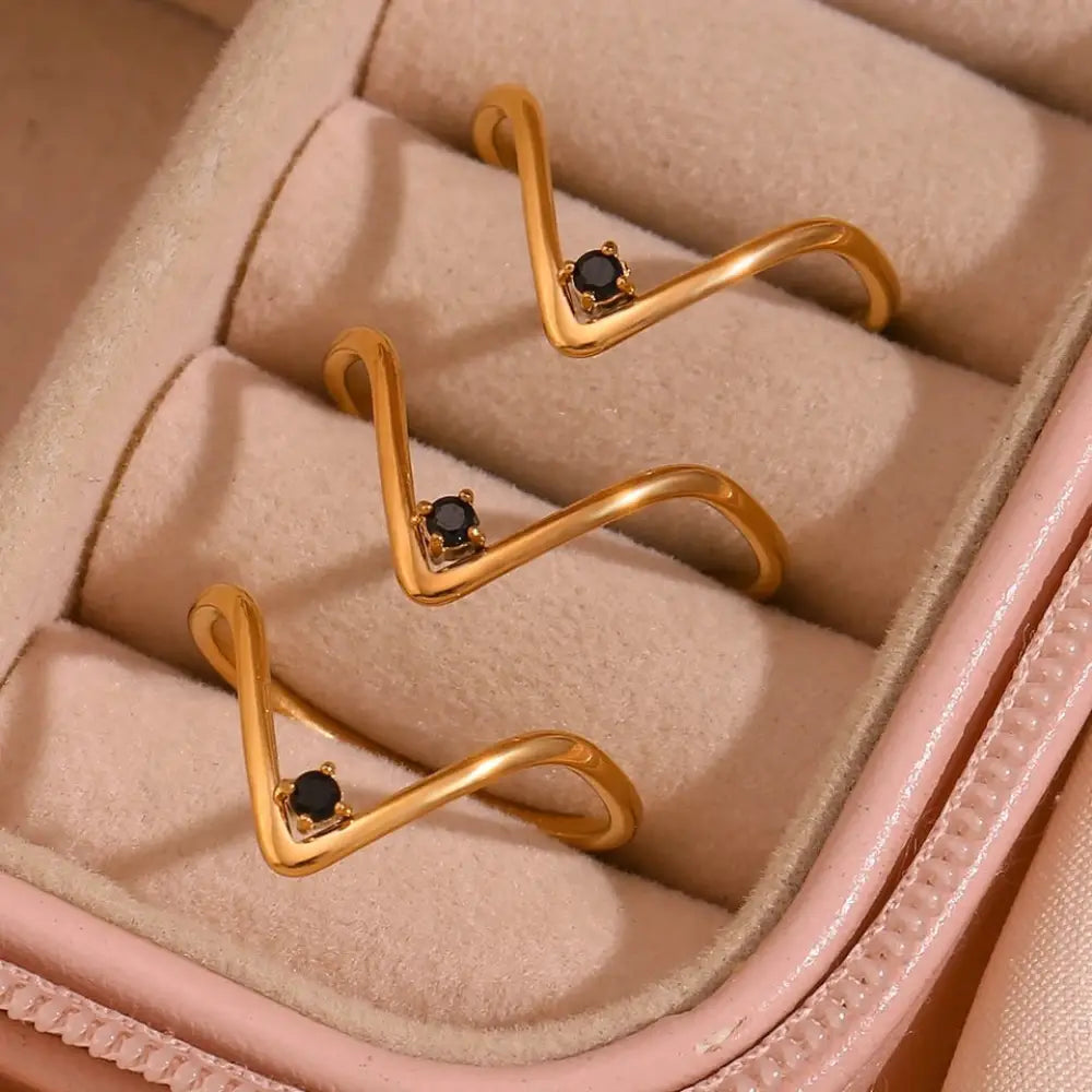 Cosmo gold v shape waterproof ring with gold-toned wavy design and black gemstones in a delicate style