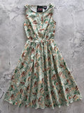 A sleeveless light green cotton midi dress with brown house and foliage print titled Cottage Tales Green Fox Print