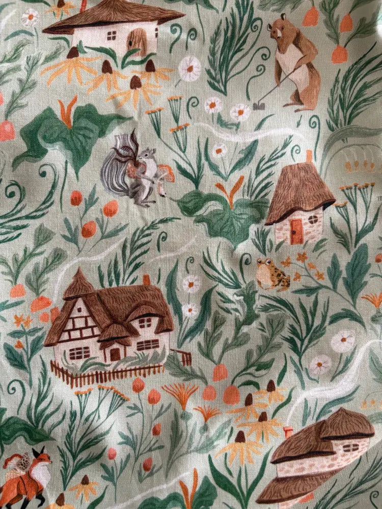 Cottage tales green fox print cotton midi dress with light green fabric featuring cottages and woodland animals pattern
